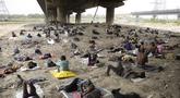 Para tunawisma tidur di bawah naungan jembatan layang pada hari yang panas di New Delhi, Jumat (20/5/2022). Ibu kota India dan sekitarnya tengah menghadapi kondisi gelombang panas yang ekstrem. (AP Photo/Manish Swarup)