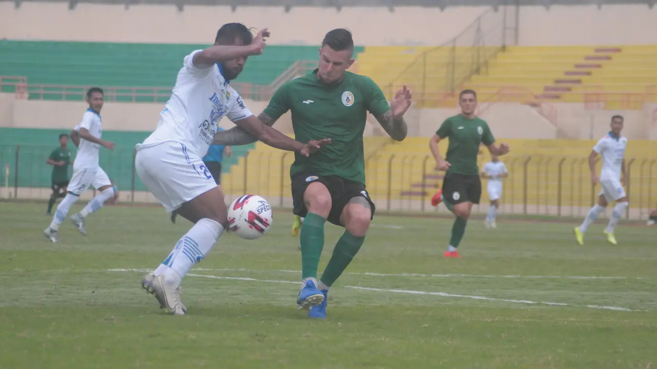 Bek PSS Sleman, Aaron Evans (hijau) berduel dengan striker Persib Bandung, Zulham Zamrun