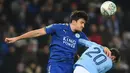 Bek Leicester City Harry Maguire berebut bola dengan gelandang Manchester City, Bernardo Silva pada perempat final Piala Liga Inggris di King Power Stadium, Selasa (19/12). Manchester City melaju ke semifinal usai menang dengan skor 4-3. (Paul ELLIS/AFP)