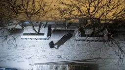 Seorang perempuan berjalan di jalan yang tertutup salju di bagian Ridgewood di distrik Queens, New York, Sabtu (29/1/2022). Orang-orang dari New York City hingga Maine terbangun karena salju tebal dan angin kencang saat badai salju lebat Nor'easter yang kuat melanda. (AP Photo/Brittainy Newman)