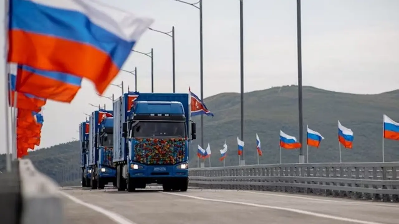 Truk-truk Korea Utara melintasi jembatan baru Rusia-Korea Utara di atas Sungai Tumen saat upacara peresmian pada Senin (7/9/2026), dengan bendera Rusia berkibar di sekitar lokasi.