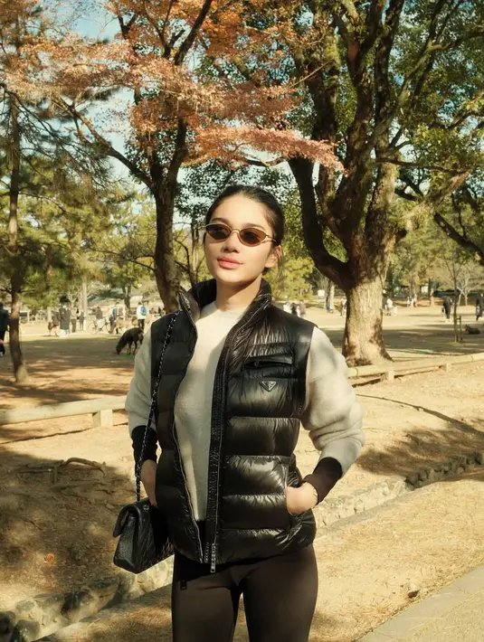 Azizah Salsha tampil edgy dengan padu padan sweater berwarna beige, vest hitam, legging hitam, dan boots berwarna senada. Penampilannya semakin manis dengan sentuhan kacamata hitam. [@azizahsalsha_].