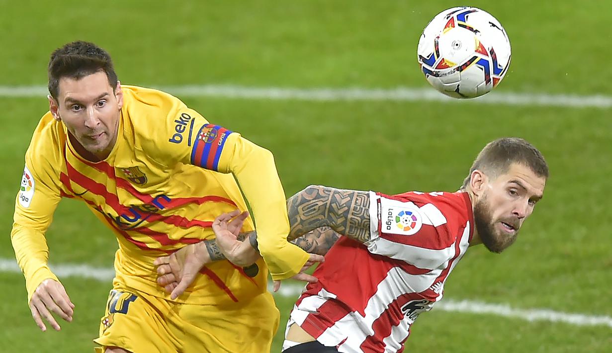 Striker Barcelona, Lionel Messi (kiri) berebut bola dengan bek Athletic Bilbao, Inigo Martinez dalam laga lanjutan Liga Spanyol 2020/21 di San Mames Stadium, Bilbao, Rabu (6/1/2021). Barcelona menang 3-2 atas Athletic Bilbao. (AFP/Ander Gillenea)