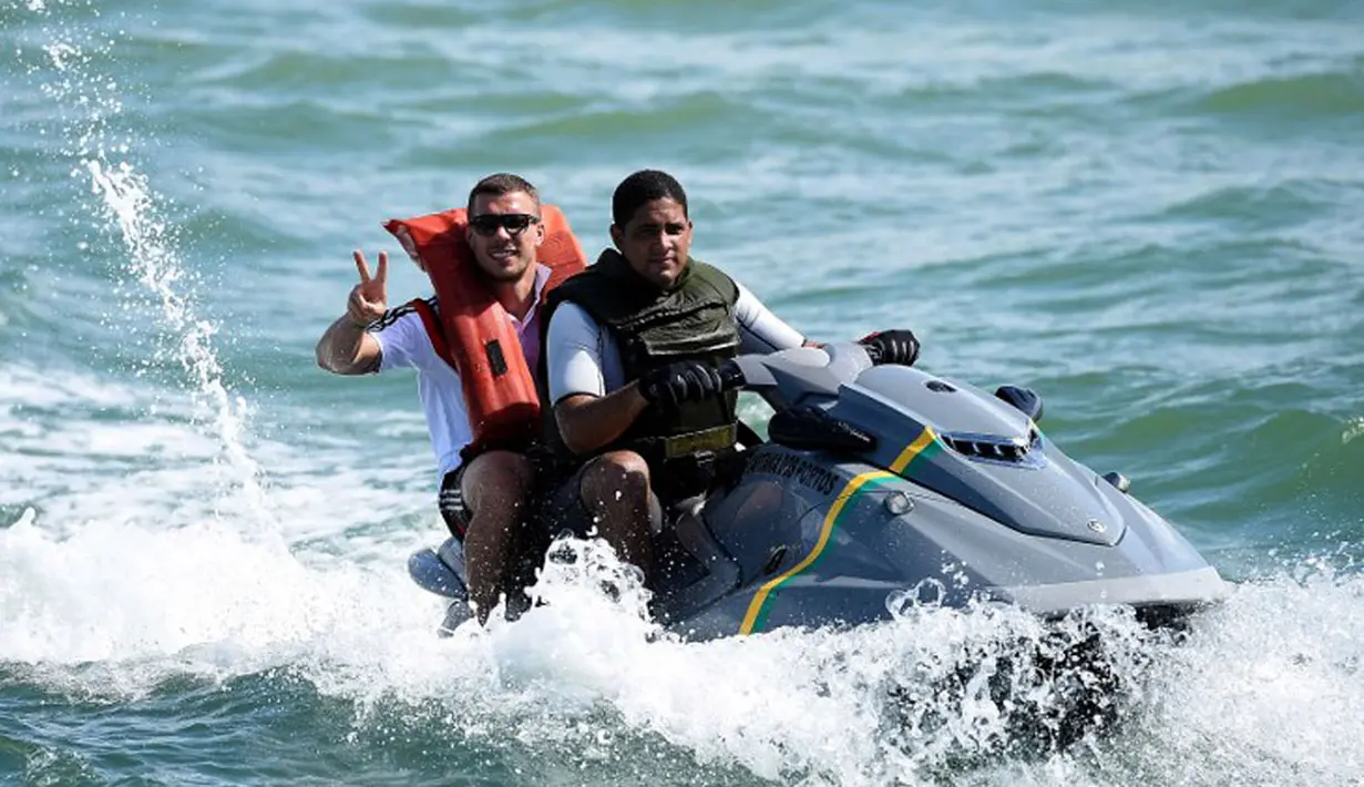 Bersama petugas keamanan pantai Brasil, pemain depan Timnas Jerman, Lukas Podolski (belakang) berlayar menggunakan jetski di salah satu pantai dekat Santo Andre, Sao Paolo, (10/6/2014). (AFP PHOTO/Markus Gilliar)