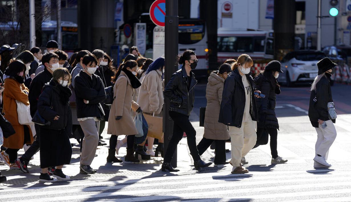 Warga yang memakai masker untuk membantu mengekang penyebaran COVID-19 menyeberang jalan di Tokyo, Jepang, 21 Januari 2022. Jepang memperluas pembatasan COVID-19 karena varian Omicron yang menyebabkan kasus melonjak ke level tertinggi baru di wilayah metropolitan. (AP Photo/Eugene Hoshiko)