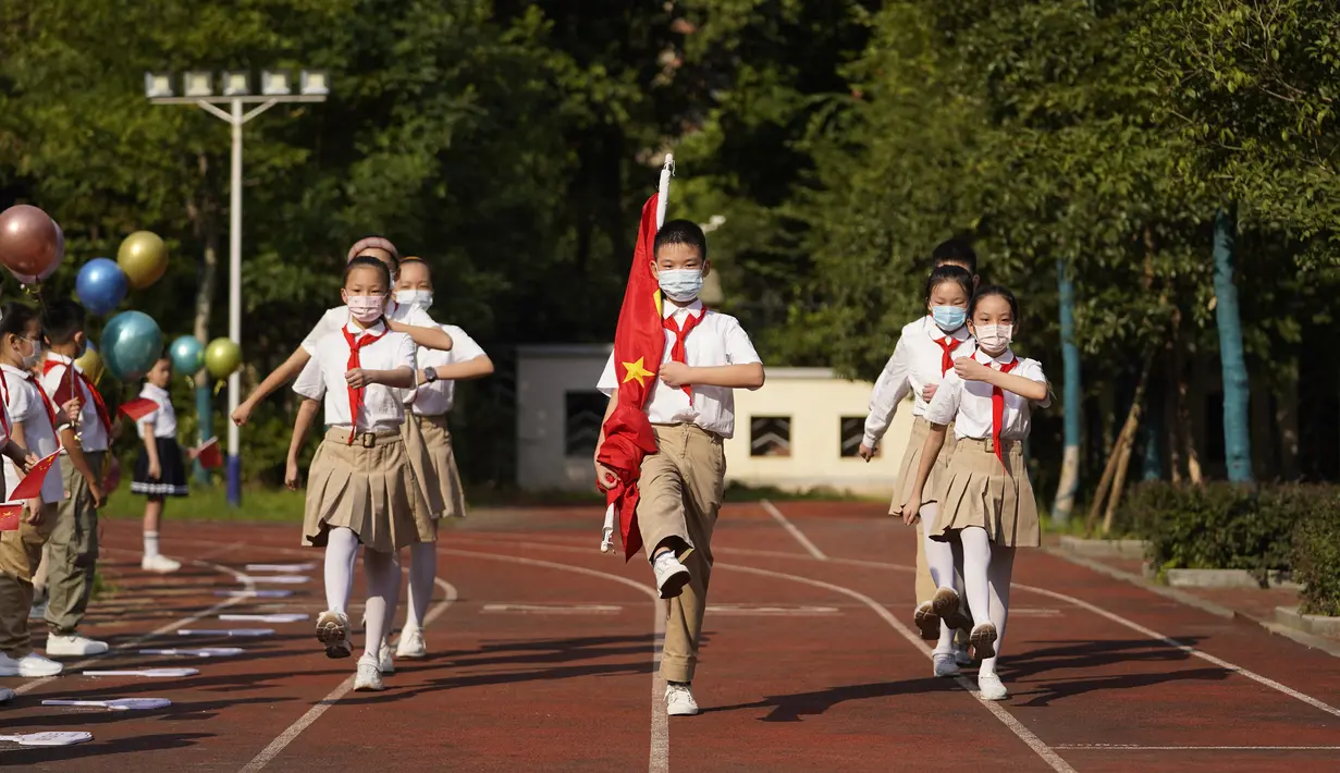 Para siswa menghadiri upacara pengibaran bendera pada hari pertama semester baru di Wuhan, Provinsi Hubei, China, 1 September 2021. Pemerintah China memutuskan pemberlakuan belajar tatap muka setelah percaya diri menangani pandemi COVID-19. (STR/AFP)
