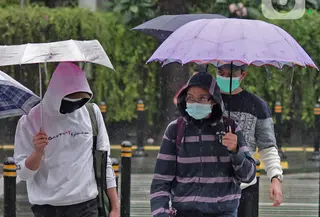 Warga menggunakan payung beraktivitas di kawasan Bundaran HI, Jakarta, Minggu (24/1/2021). Badan Meteorologi Klimatologi dan Geofisika (BMKG) mencatat sebagian besar wilayah Indonesia telah memasuki masa puncak musim hujan. (Liputan6.com/Herman Zakharia)