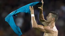 Pemain Real Madrid, Cristiano Ronaldo mengangkat jerseynya tinggi-tinggi di hadapan suporter Camp Nou pada leg pertama Piala Super Spanyol, Senin (14/8). Aksi selebrasi Ronaldo ini serupa yang dilakukan Lionel Messi sekitar April lalu. (STRINGER/AFP)