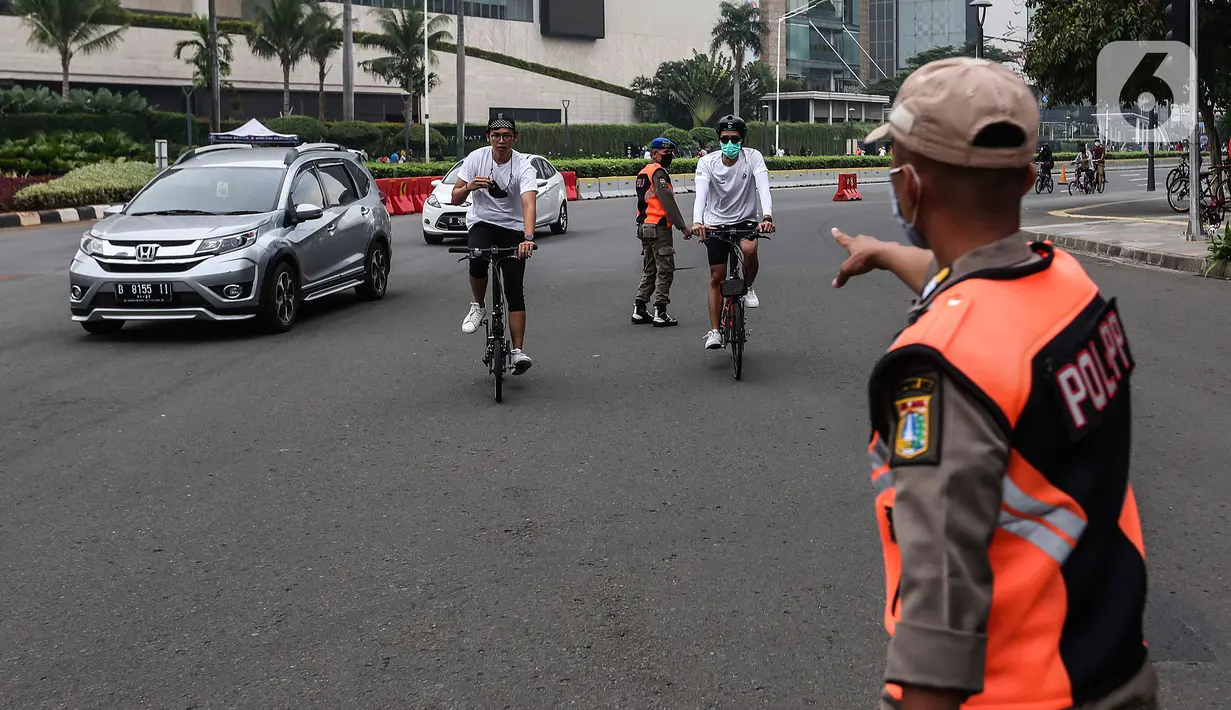 Satpol PP menegur pesepeda yang tidak mengenakan masker dengan benar saat melintas di kawasan Bundaran HI, Jakarta, Minggu (17/1/2021). Sosialisasi penggunaan masker untuk mencegah penularan virus corona COVID-19 masih saja diabaikan karena rendahnya kesadaran masyarakat. (Liputan6.com/Johan Tallo)