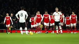 Para pemain Manchester United menunggu para pemain Arsenal yang baru saja merayakan gol yang dicetak Bukayo Saka dalam laga pekan ke-21 Premier League di Emirates Stadium, Minggu (22/1/2023). Arsenal menang 3-2 atas MU. (AP Photo/Ian Walton)