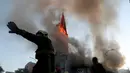 Petugas pemadam kebakaran berdiri di depan gereja La Asuncion yang terbakar saat puluhan ribu orang berunjuk rasa di Kota Santiago, Chile, Minggu (18/10/2020). Demonstrasi itu digelar untuk memperingati satu tahun protes besar menuntut kesetaraan di Chile. (AP Photo/Esteban Felix)
