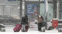 Orang-orang menuju ke stasiun bus di tengah hujan salju lebat di Gwangju, Korea Selatan, Selasa, 24 Januari 2023. Suhu ekstrem tidak hanya melanda Korea Selatan, tetapu juga negara Asia Timur lainnya, seperti Korea Utara, China, dan Jepang. (Chun Jung-in/Yonhap via AP)
