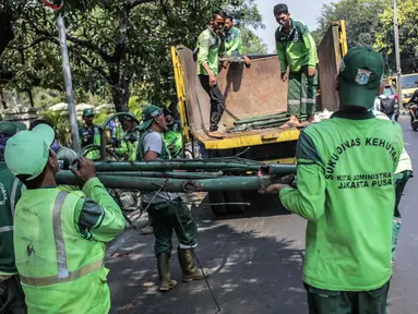 Petugas Suku Dinas Kehutanan Jakarta Pusat mengangkut pagar yang dirusak pengunjuk rasa ke dalam truk usai demonstrasi di depan TPU Karet, Jakarta, Selasa (1/10/2019). Pengerusakan dilakukan pengunjuk rasa saat terlibat bentrok dengan polisi di kawasan tersebut. (Liputan6.com/Faizal Fanani)