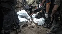 Tim forensik Malaysia memeriksa tubuh manusia yang baru digali dari sebuah makam tak bertanda di Bukit Wang Burma, dekat perbatasan Malaysia-Thailand, (26/5/2015). 139 kuburan massal yang berisi kerangka orang ditemukan.  (AFP PHOTO/MOHD RASFAN)
