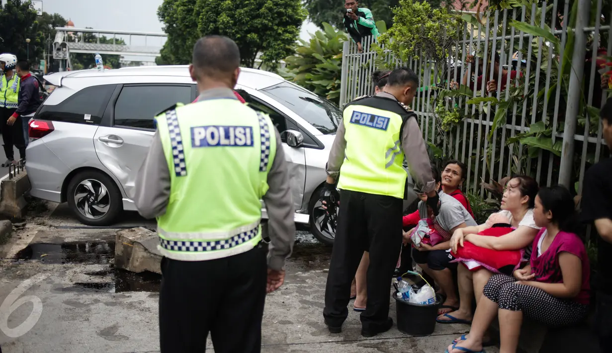 Polisi berjaga didekat mobil yang menabrak separator busway matraman arah kampung melayu, Jakarta, Sabtu (25/2). (Liputan6.com/Faizal Fanani)