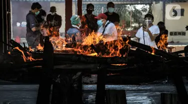 Petugas mengenakan APD saat proses kremasi jenazah pasien Covid-19 di Krematorium Cilincing, Jakarta Utara, Minggu (25/7/2021). Layanan kremasi jenazah pasien Covid-19 di Krematorium Cilincing terus bergeliat sejak dibuka pada 19 Juli 2021. (merdeka.com/Iqbal S Nugroho)