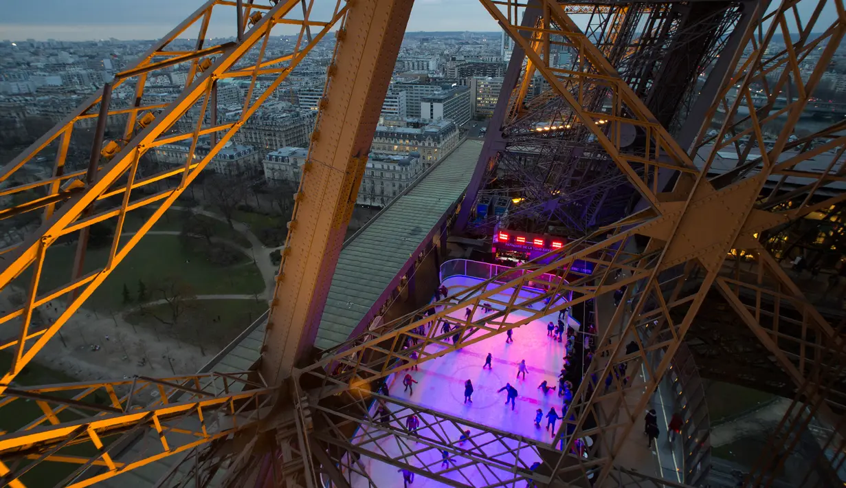 Wisatawan menikmati arena seluncur es yang dibuka di lantai 1 Menara Eiffel, Paris, 19 Desember 2016. Arena ice skating ini bisa dinikmati secara gratis hanya dengan membeli tiket kunjungan Eiffel seharga €9 atau sekitar Rp 139 ribu (AFP PHOTO/JOEL SAGET)