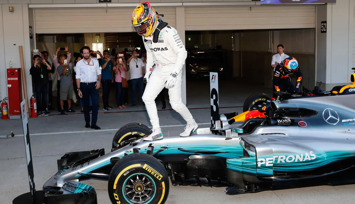 Lewis Hamilton keluar dari mobil untuk merayakan kemenangannya pada GP F1 Jepang di Sirkuit Suzuka, Jepang, (8/10). Hamilton mengoleksi 306 poin atau unggul 59 poin dari Vettel yang gagal finis di Suzuka. (AP Photo / Eugene Hoshiko)