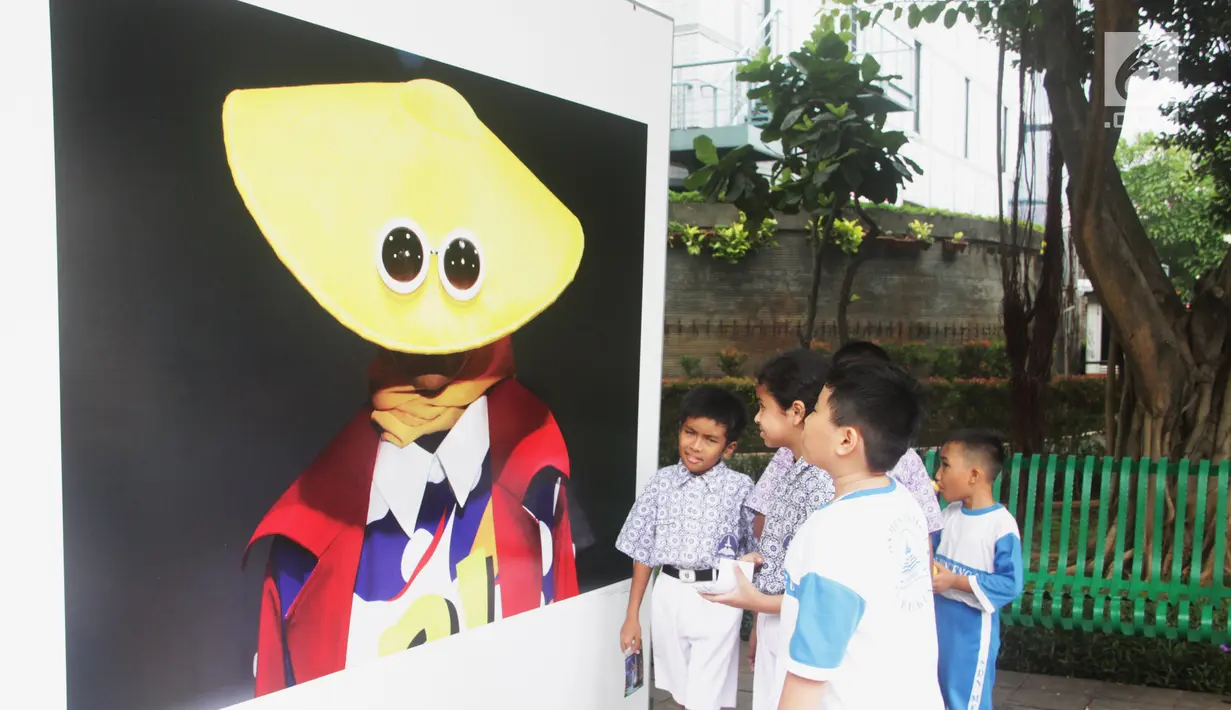 Siswa SD Negeri Menteng 01 mengamati karya foto yang dipamerkan dalam pameran fotografi Rekam Jakarta di Taman Menteng, Kamis (29/8/2019). Kegiatan tersebut dalam rangka edukasi bagi siswa mengenal profesi foto jurnalistik. (Liputan6.com/Marsha Aulia)