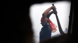 Seorang umat Hindu mengayunkan parang saat ingin memenggal seekor kerbau dalam Festival Gadhimai di Bariyarpur, 160 km dari Kathmandu, Nepal (3/12/2019). Festival ini dikenal sebagai ritual pengorbanan hewan terbesar di dunia. (AFP/Prakash Mathema)