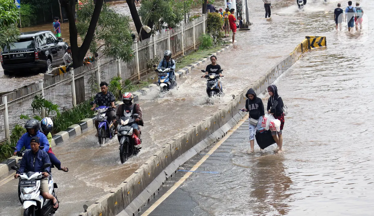 Pengendara dan pejalan kaki melewati perempatan Green Garden, Kedoya, Jakarta, Jumat (3/1/2020). Hingga hari ke-3, banjir masih menggenangi sekitar kawasan perempatan Green Garden, Kedoya akibatnya pengendara harus lebih waspada menghindari mesin kemasukan air. (Liputan6.com/Helmi Fithriansyah)