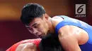 Pegulat putra Indonesia, Muhammad Aliansyah dan Zhang Gaoquan dari China saling mengunci saat bertarung pada kelas putra 67 Kg Asian Games 2018 di arena gulat JCC Senayan, Selasa (21/8). (Liputan6.com/Fery Pradolo)