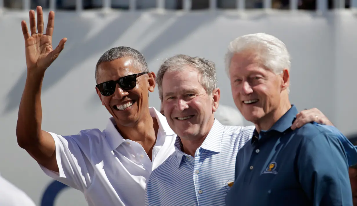 Mantan Presiden AS, Barack Obama, George W Bush dan Bill Clinton menyapa penonton saat upacara pembukaan pertandingan golf President Cup di New Jersey, Kamis (28/9). Ini pertama kalinya tiga presiden datang bersama di turnamen tersebut. (AP/Julio Cortez)