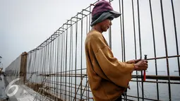 Pekerja mengaitkan kawat untuk pembangunan Dam di kawasan Pasar Ikan Muara Baru, Jakarta, Senin (3/10). Pemprov DKI akan mempercepat pembangunan tanggul laut guna mencegah terjadinya kembali banjir rob di kawasan tersebut. (Liputan6.com/Faizal Fanani)