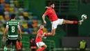 Gelandang Benfica, Gabriel (kanan) menendang bola sambil melompat dalam laga lanjutan Liga Portugal 2020/21 melawan Sporting Lisbon di Jose Avalade Stadium, Lisbon, Senin (1/2/20201). Benfica kalah 0-1 dari Sporting. (AFP/Patricia De Melo Moreira)