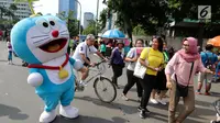 Seniman berkostum boneka Doraemon menggoda warga saat kegiatan Car Free Day di Bundaran HI di Jakarta, Minggu, (12/11). Kegiatan tersebut bermaksud untuk menghibur warga. (Liputan6.com/Fery Pradolo)