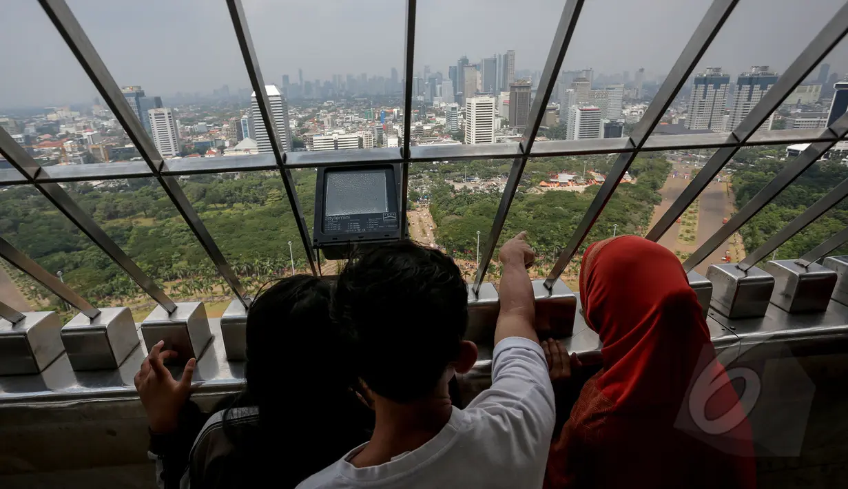 Pengunjung melihat Jakarta dari ketinggian puncak Monumen Nasional (Monas), Jakarta, Kamis (14/5/2015). Jumlah pengunjung mengalami peningkatan tinggi bertepatan libur kenaikan Isa Almasih. (Liputan6.com/Faizal Fanani)