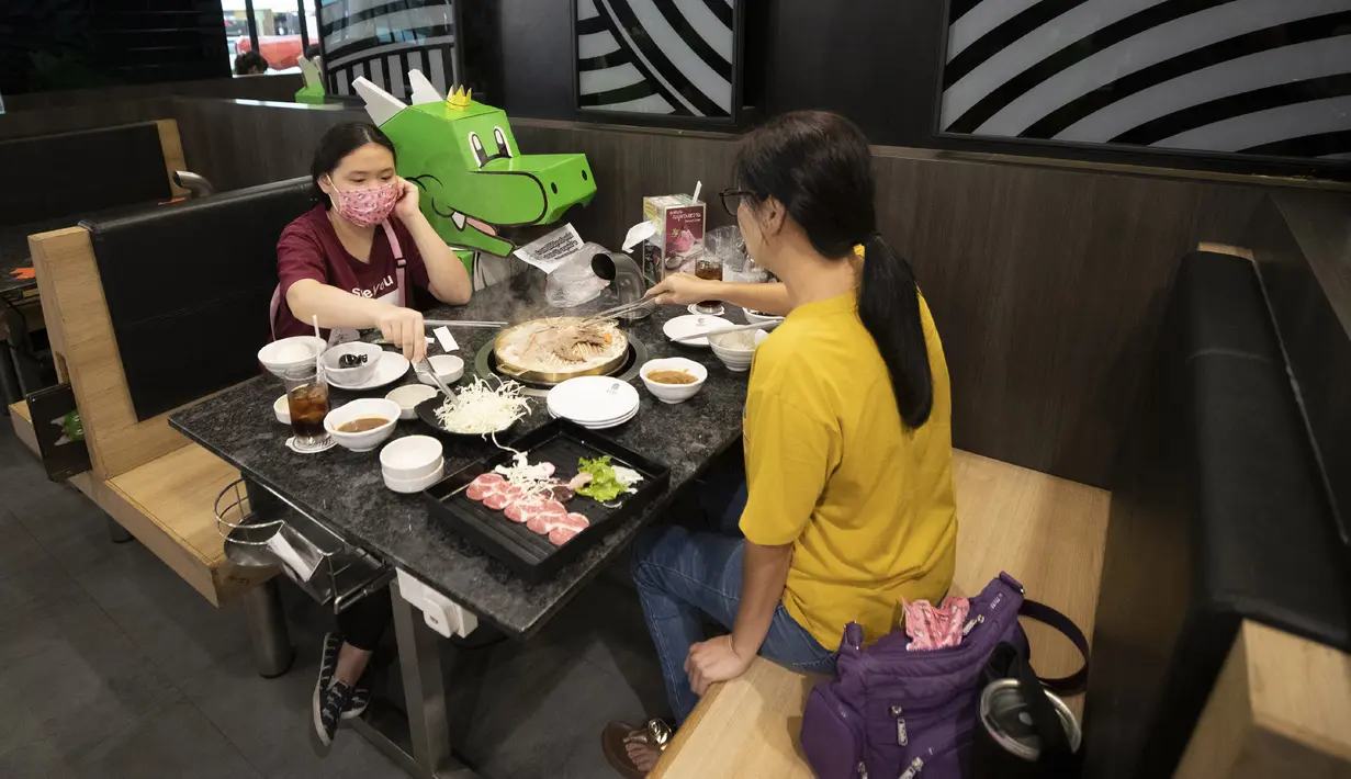 Pelanggan duduk bersebelahan dengan boneka kartun naga yang digunakan restoran untuk menjaga jarak fisik di Bangkok, Thailand, Senin (18/5/2020). Pemerintah Thailand mengizinkan pusat perbelanjaan dan bisnis kembali dibuka setelah sebelumnya ditutup karena pandemi COVID-19. (AP Photo/Sakchai Lalit)