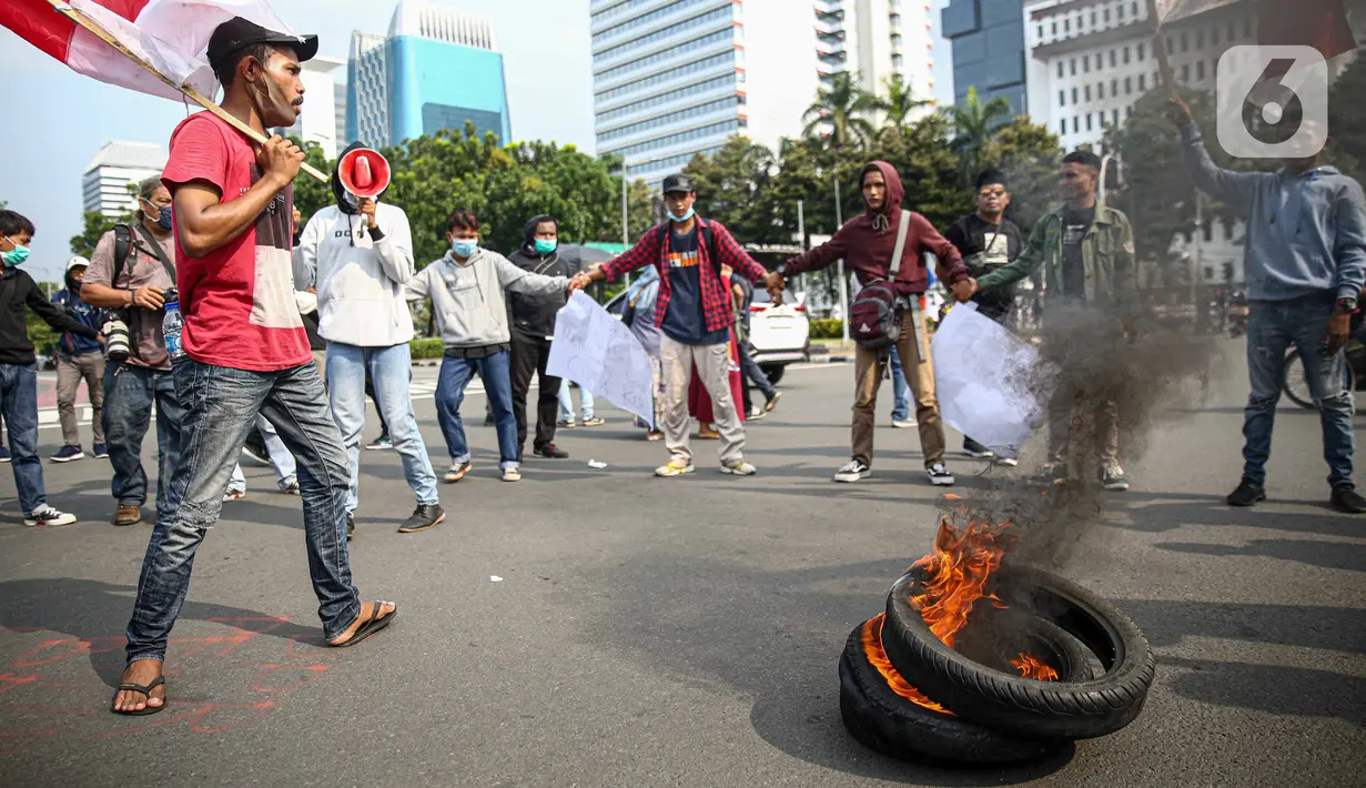 Massa Himpunan Mahasiswa Islam (HMI) membakar ban bekas saat berunjuk rasa menentang UU Cipta Kerja di kawasan Patung Kuda, Jakarta, Rabu (28/10/2020). Massa meminta Presiden Joko Widodo segera mencabut UU Cipta Kerja melalui Peraturan Pemerintah Pengganti Undang-Undang. (Liputan6.com/Faizal Fanani)