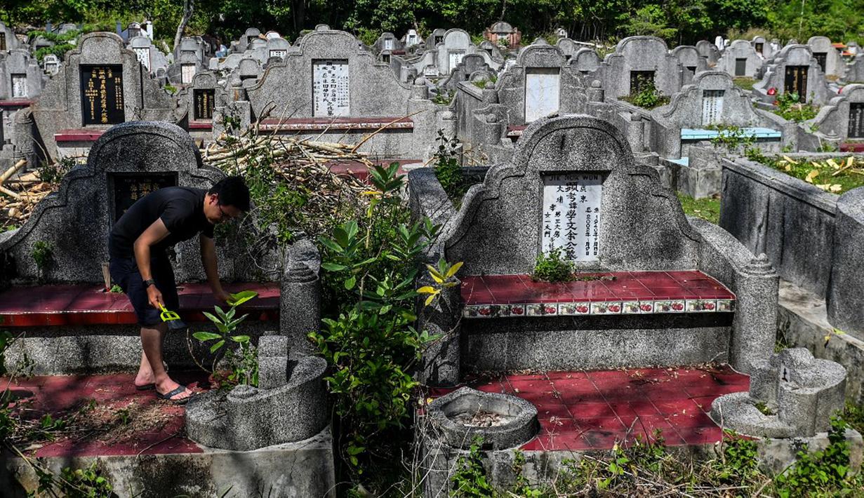 Warga keturunan Tionghoa membersihkan makam keluarga saat Festival Cheng Beng di Pemakaman Tionghoa di Japakeh, Banda Aceh, Aceh, Minggu (26/3/2023). (CHAIDEER MAHYUDDIN/AFP)