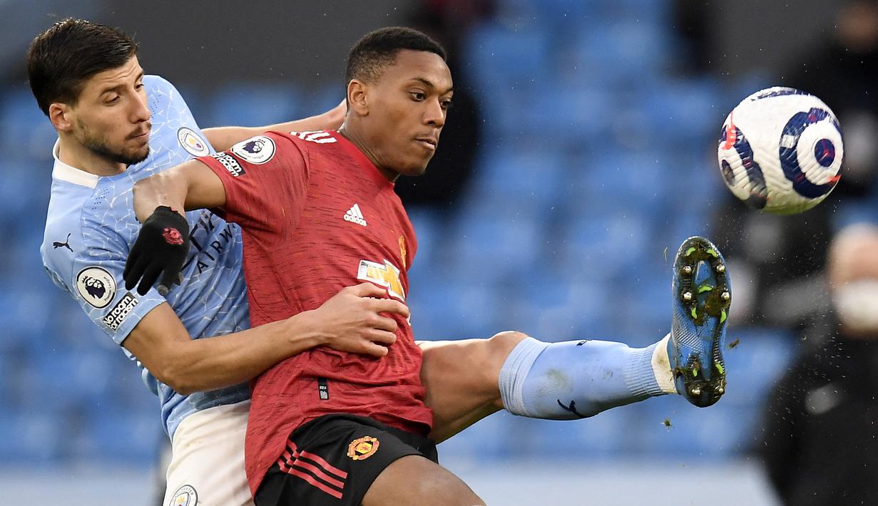 Striker Manchester United, Anthony Martial (kanan) berebut bola dengan bek Manchester City, Ruben Dias dalam laga lanjutan Liga Inggris 2020/21 di Etihad Stadium, Minggu (7/3/2021). MU menang 2-0 atas Mancity. (AFP/Peter Powell/Pool)