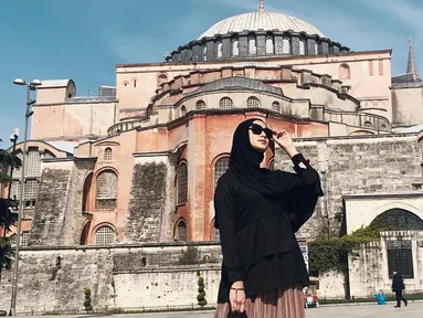 Potret cantik Citra Kirana kenakan hijab dan atasan warna hitam dengan kacamatanya, berada di depan Hagia Sophia, yang dahulunya Katedral, Masjid dan kini jadi museum di Istanbul, Turki. (Liputan6.com/IG/@citraciki)