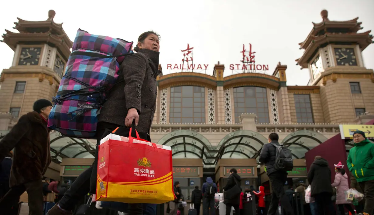 Seorang wanita membawa barang bawaannya di luar Stasiun Kereta Api Beijing, China (9/2). Sambut perayaan Imlek 2018, Jutaan warga China mulai memenuhi stasiun, bandara dan jalan yang diperkirakan akan dimulai akhir pekan ini. (AP Photo/Mark Schiefelbein)