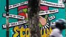 Pengendara melintas di depan mural berisi kritik terhadap kinerja polisi di Lapangan Bhayangkara Mabes Polri, Jakarta, Minggu (31/10/2021). Sejumlah mural berisi kritik terhadap polisi dipamerkan usai mengikuti ajang Mural Festival 2021 Piala Kapolri 2021. (Liputan6.com/Helmi Fithriansyah)