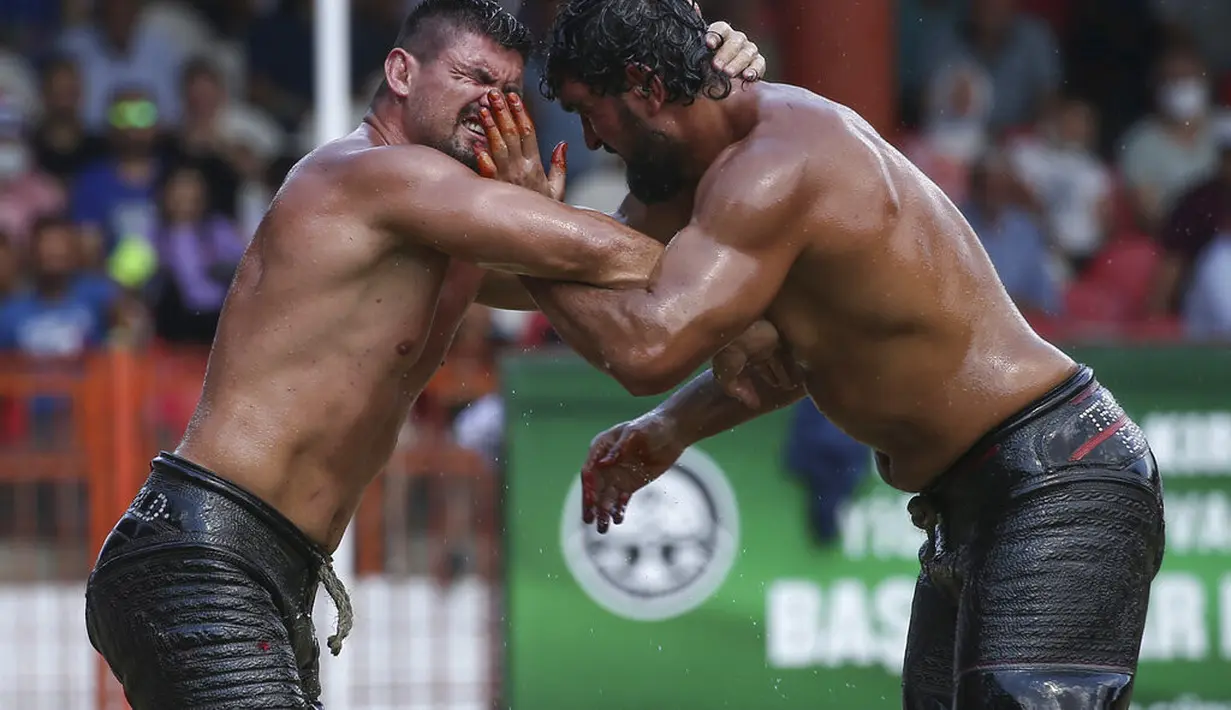 Pegulat Ismail Koc (kanan) dan Faruk Akkoyun bertanding di semifinal kejuaraan gulat minyak Kirkpinar tahunan ke-660, di Edirne, Turki barat laut, Minggu (11/7/2021). (AP Photo/Emrah Gurel)