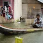 Deri Mustapa, warga Desa Buhu, Kecamatan Telaga Jaya, Kabupaten Gorontalo saat mengayuh perahu menuju rumahnya (Arfandi/Liputan6.com)