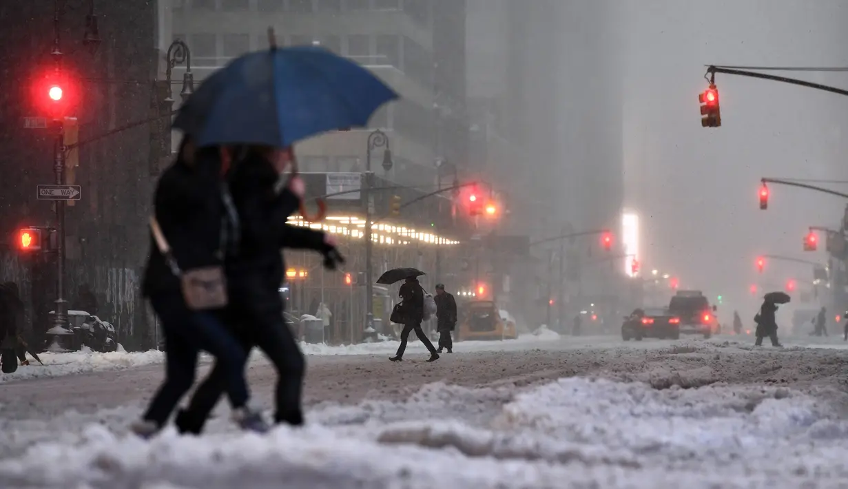 Warga berjalan di New York, yang terkena dampak badai salju, Selasa (14/3). Badai salju menghantam hampir separuh wilayah Amerika Serikat ketika sebagian besar wilayah Pantai Timur mengalami badai musim dingin paling buruk. (Jewel SAMAD/AFP)