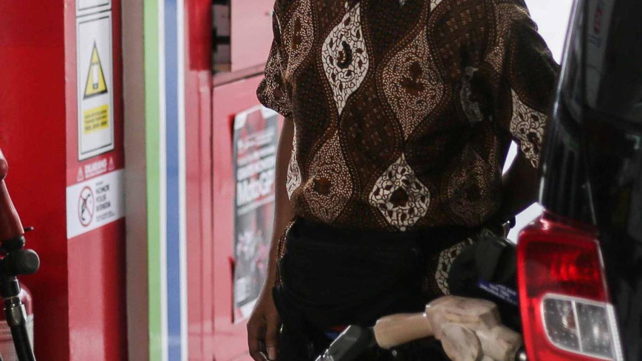 Petugas berpakaian batik saat melayani konsumen yang membeli bahan bakar minyak (BBM) di SPBU MT Haryono.