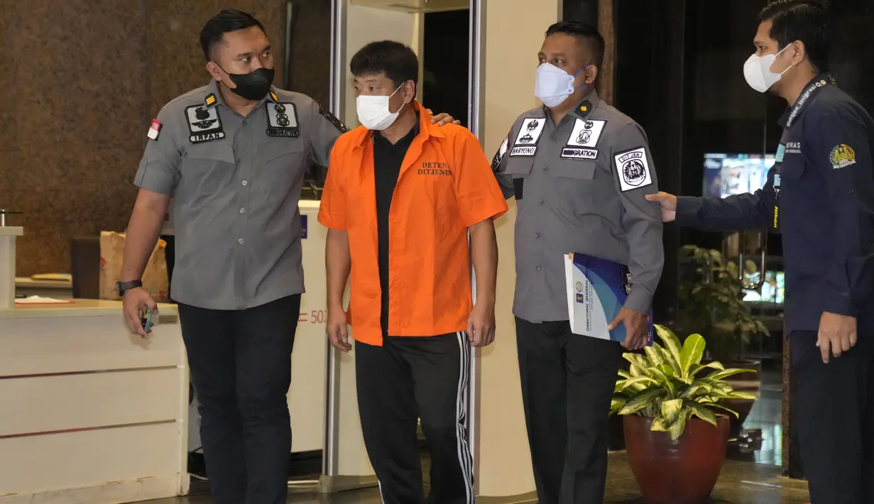 Petugas Imigrasi Indonesia mengawal buronan Jepang Mitsuhiro Taniguchi sebelum dideportasi di Jakarta, Rabu (22/6/2022). Mitsuhiro Taniguchi diamankan di daerah Kalirejo, Lampung Tengah pada Selasa (7/6/2022) terkait kasus dugaan penipuan dana bantuan sosial (bansos) Covid-19 yang tengah diusut pihak kepolisian Jepang. (AP Photo/Dita Alangkara)