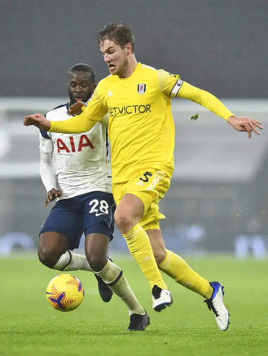 Pemain Fulham Joachim Andersen (kanan) berebut bola dengan pemain Tottenham Hotspur Tanguy Ndombele pada pertandingan Liga Inggris di Stadion Tottenham Hotspur, London, Inggris, Rabu (13/1/2021). Pertandingan berakhir dengan skor 1-1. (Glyn Kirk / Pool via AP)