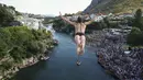 Seorang penyelam melompat dari Jembatan Tua selama kompetisi menyelam dari ketinggian ke-456 di Mostar, Bosnia, Minggu (31/7/2022). Penyelam berlari sebelum melompat dari jembatan, jatuh ke sungai dan terbang d dara seperti burung melakukan trik. (AP Photo/Armin Durgut)