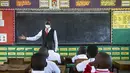 Seorang guru menyambut kembali siswa selama pelajaran di kelas pada hari pertama pembukaan kembali sekolah di Kampala pada 10 Januari 2022. Sekolah-sekolah di Uganda dibuka kembali untuk siswa pada Senin, mengakhiri penutupan sekolah terlama di dunia akibat pandemi COVID-19. (Badru KATUMBA/AFP)