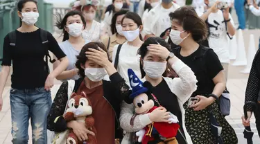 Pengunjung mengenakan masker guna melindungi diri dari virus corona berjalan menuju pintu masuk Tokyo Disneyland di Urayasu, dekat Tokyo, Rabu (1/7/2020). Tokyo Disneyland dibuka kembali untuk pertama kalinya dalam empat bulan setelah menangguhkan operasi karena kekhawatiran Covid-19. (AP/Koji Sasah