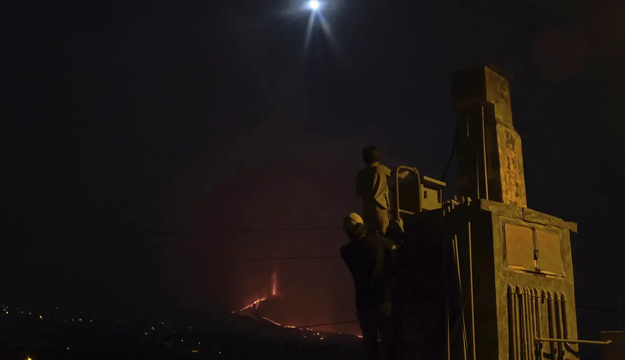 Orang-orang melihat ke gunung berapi Cumbre Vieja yang terus meletus di pulau Canary La Palma, Spanyol pada Sabtu (16/10/2021). Gunung berapi di salah satu Kepulauan Canary di barat laut Afrika sejauh ini telah menghancurkan lebih dari 1.800 bangunan, sebagian besar rumah. (AP Photo/Daniel Roca)