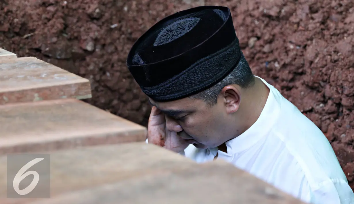 Presenter Farhan saat mengazdani anak pertamanya Muhammad Ridzky Khalid di TPU Tanah Kusir, Jakarta, Senin (21/12). Ridzky menghebuskan nafas terakhirnya di usia 16 tahun pada Minggu, (20/12/2015) pukul 13.40 WIB. (Liputan6.com/Immanuel Antonius)