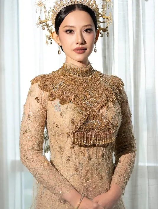Athina kenakan dress berpotongan mermaid full payet emas dengan cape lace panjang rancangan Biyan [@leonardowedding]